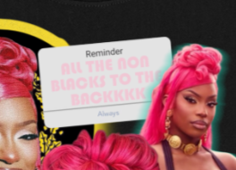 Person with pink hair wearing a black shirt with text and graphic design.